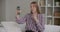 Young woman is filming training video by camera of smartphone, sitting at home, taking selfies