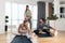 Young woman fitness and yoga instructor helping couple in their home for workout exercises. Female coach working with clients