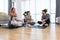 Young woman fitness and yoga instructor helping couple in their home for workout exercises. Female coach working with clients