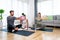 Young woman fitness and yoga instructor helping couple in their home for workout exercises. Female coach working with clients