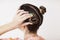 A young woman fixes her hair bun.