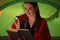 Young woman with flashlight reading book in tent