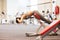 Young woman flexing back muscles on bench in gym