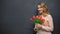 Young woman with flowers standing near blackboard, celebrating teachers day