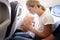 Young woman flying in airplane and breathing into paper bag