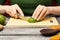 Young woman with fresh avocado at the table. The girl cuts the avocado