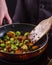 Young woman fries Brussels sprouts on a frying pan