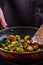 Young woman fries Brussels sprouts on a frying pan