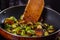 Young woman fries Brussels sprouts on a frying pan