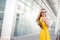 Young woman in front of airport in yellow dress