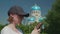 Young woman frowns, shakes head, swipes on smartphone, church in background