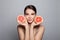 Young woman with fruits on gray background. Pretty model showing grapefruits, portrait