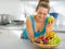 Young woman with fruits plate eating apple