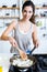 Young woman frying onion into the pan in the kitchen.