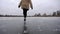 Young woman in fur coat training rotation skills on frozen river. Girl shod in figure skates sliding on ice rink outdoor