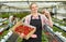 Young woman gardener in apron pholding crate with fresh strawberries