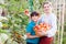 Young woman gardener with small boy holding basket with tomatoes