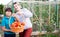 Young woman gardener with small boy holding basket with tomatoes