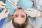 Young woman getting dental treatment closeup, hands of dentist and assistant makes treatment procedures to female