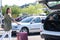 Young woman getting her suitcase out from the luggage boot of the car