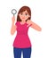 Young woman or girl holding a magnifying glass and making thumbs down gesture sign. Person showing magnifier lens.