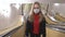 Young woman-girl in protective sterile medical face mask sitting on a bench and waiting for public transport on metro station, vir