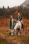 A young woman and a girl with red long hair walk in the wineries in the fall and ride horses