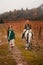 A young woman and a girl with red long hair walk in the wineries in the fall and ride horses