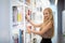 Young woman or girl standing in bookstore or library and look on book