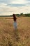 Young woman girl standing with her back with open arms to the sunset on a wheat field in the countryside