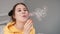 young woman girl in yellow making soap bubbles on grey background. happy, exited. slow motion