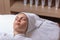 A young woman is given a rejuvenating mask of green algae on her face