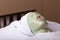 A young woman is given a rejuvenating mask of green algae on her face