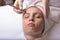 A young woman is given a rejuvenating mask of green algae on her face