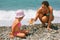 Young woman gives starfish to girl on beach