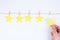 Young woman is giving her feedback by placing fifth star to the rating holding small star isolated white background