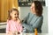 Young woman giving pill to her daughter at table