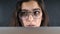 Young woman with glasses eyes looking behind monitor, close up with reflection