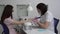 Young woman with glasses in a manicure salon. A manicurist uses a drill machine to remove nails.