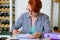 Young woman with glasses with red short hair works with documents at the desk