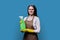 Young woman in gloves apron with organic detergent on blue background