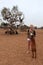 Young woman with a goat and tree with goats on the background.