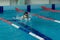 Young woman in goggles and cap swimming breaststroke stroke style in the blue water indoor race pool