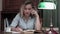 Young woman going through a book and having an angry phone conversation sitting at her desk