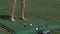 Young woman golf player training on green with club. Girl kick the ball