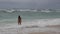 Young woman with graceful slim figure is wearing open swimsuit is walking over a tropical beach