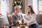 Young woman with grandfather indoors at home at Christmas, looking at photo album.