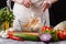 A young woman in a gray apron mixes a salad of cabbage