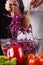 A young woman in a gray apron mixes a salad of red cabbage