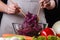 A young woman in a gray apron mixes a salad of red cabbage